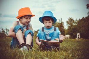 Two children reading a book outdoors